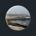 Morro Bay California Coastal Photography Knapp<br><div class="desc">A foggy overcast day in Morro Bay California with the ocean waves hitting the rocks on the shore in this beach photograph souvenir. This seaside travel photo keepsake button features black cursive script above the beach rocks and grey sky.</div>