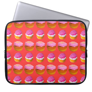 Muffins, muffinsar med vit och rosa kräm på en r laptop fodral