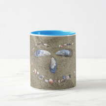 Mugggultansikte som göras i sanden med snäckor