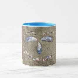 Mugggultansikte som göras i sanden med snäckor mugg