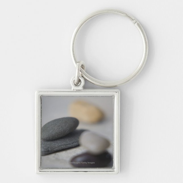 Närbild av småsten fyrkantig silverfärgad nyckelring (Framsidan)