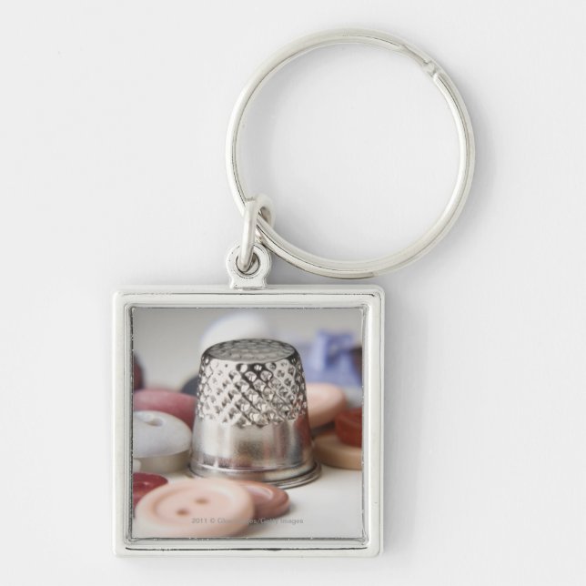 Närbilden av knäppas med ett metalllock fyrkantig silverfärgad nyckelring (Framsidan)