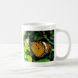 Orange, svart och vit fjäril på blad kaffemugg