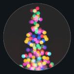 Oskarp jul Ljus Runt Klistermärke<br><div class="desc">Fira vintern-julhelgen med det här originella,  färgstarka,  abstrakten av dimmig ljus. Den båge som skapades från ljus rosa,  rött,  orange,  blått,  grönt och gult utgör formen av ett Julgran. Lodräts bakgrund är svart. Digital,  färg-fotografi. Copyright © 2012 Claire E. Skinner. Alla rättigheter förbehållna.</div>