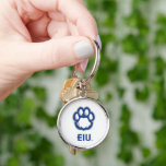 Östra Illinois Panthers Paw Print & EIU Rund Silverfärgad Nyckelring<br><div class="desc">Denna konstruktion har två olika inslag som representerar Östra Illinois Universiteten (EIU). I överkanten visas en stiliserad ritarpapp på en framträdande plats. Blåutskriften återges i blått med en grått-kontur som skapar en fetstilt och igenkännlig symbol för EIU-pantrarna. Under taputskriften presenteras förkortningen "EIU" i ett starkt, sans-serif typeface, som förstärker universiteten...</div>