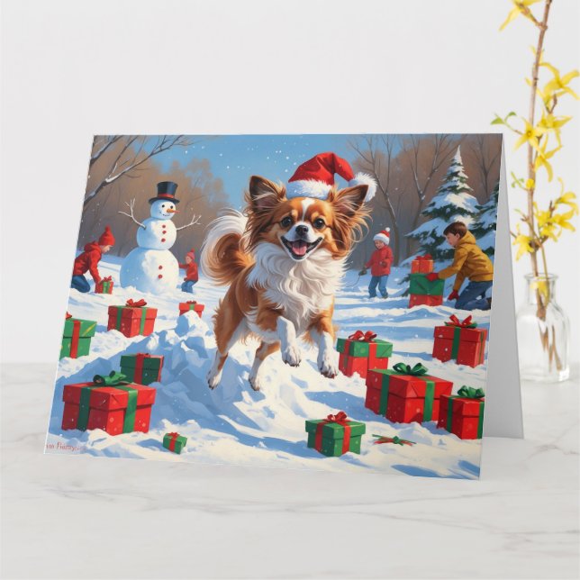 Papillon-hund springer i snö med julhatt kort (Gul blomma)