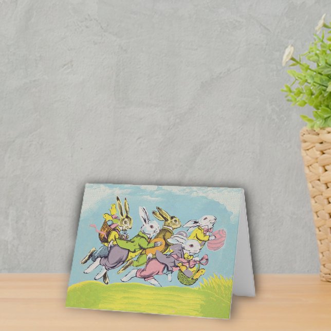 Påskharar som springer i pastellfärger helgkort (Group running Easter rabbits in pastel clothes eggs baskets in grass under blue sky on notecard.)