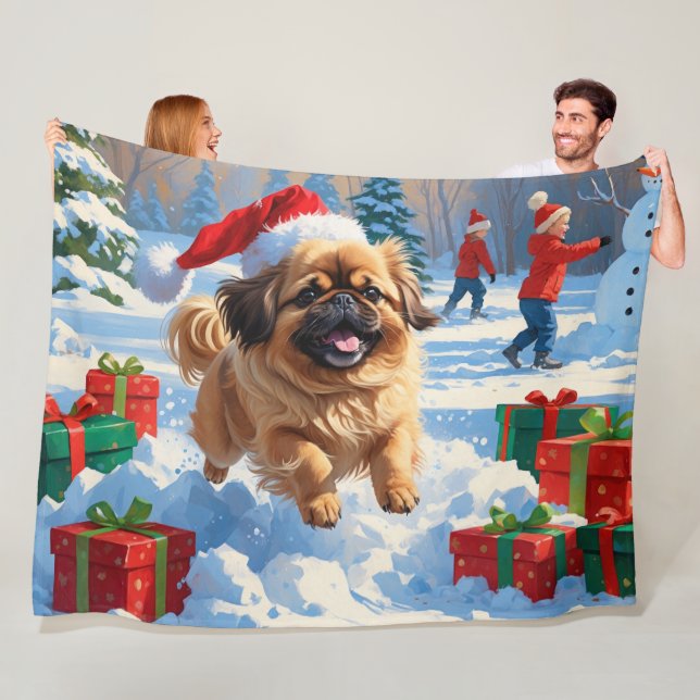 Pekingeserhund springer i snö med julhatt fleecefilt (På plats)