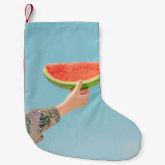Person som innehar segmenterad vattenmelon liten julstrumpa