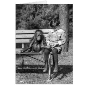 Pojken som sitter med orangutan vid nationalparken hälsningskort