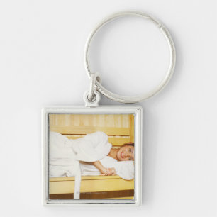 Porträtt av en ung kvinna som ljuger i en bastu fyrkantig silverfärgad nyckelring