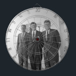 President John Kennedy & Brothers American Camelot Darttavla<br><div class="desc">Sol slog ner på de tre Kennedy-bröderna när de stod under Vita husets välkända vita portico. President John F. Kennedy, den äldsta, lutade mot en pelare, ett leende som leker på hans läppar. Hans yngre bröder, Robert och Ted, stod bredvid honom, deras ansikte en blandning av glädje och syskon rivalitet....</div>