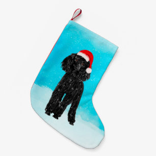 Pudelhundsitta i snö med den Santa hatten Liten Julstrumpa