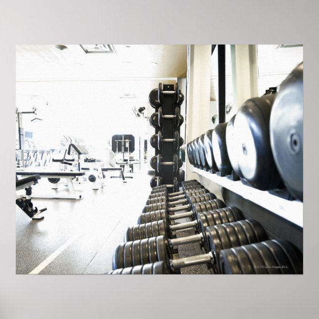 Rad med fria vikter i förgrund och motion poster (Framsidan)