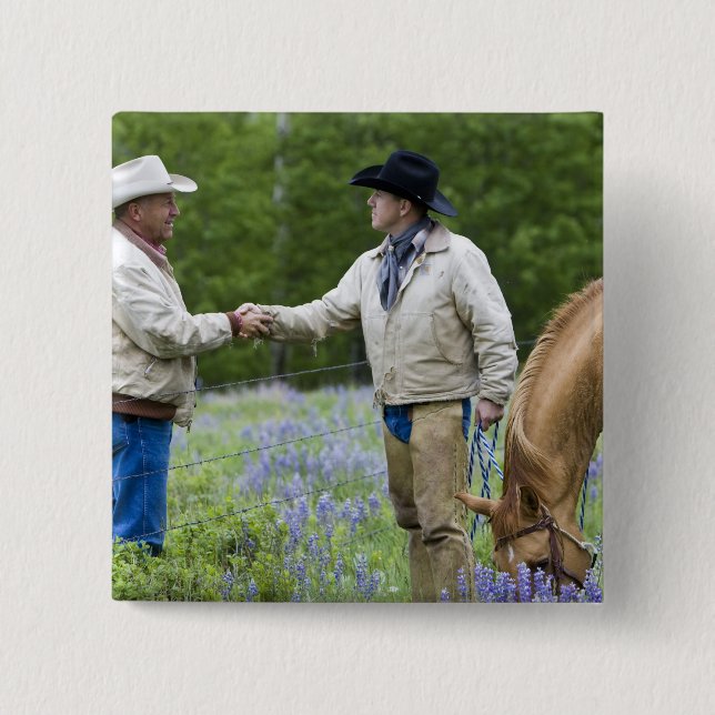 Rancher som skakar hand över stängslet i knapp (Framsida)