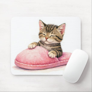 Randig kattunge som sover i en rosa toffel musmatta