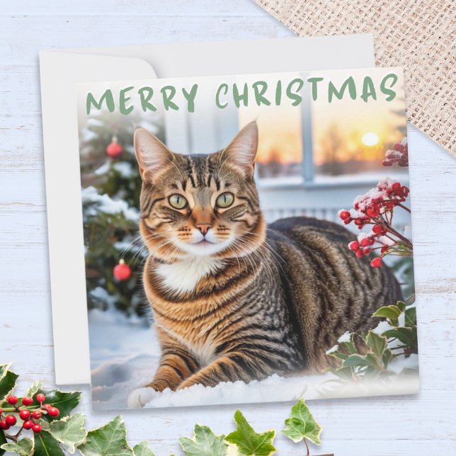 Rattkatt i snö Elegit God Jul Julkort (A Christmas card featuring a cute tabby cat in the snow, with ivy, Christmas tree and red berries
)