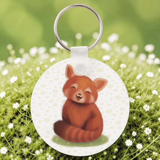 Röd Panda Nyckelring (A keychain with a hand-painted red panda, cute and smiling, laid on sunlit moss.)
