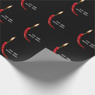 Röd peppar med ljuslåga på svart presentpapper