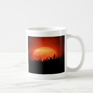 Röd solnedgång bakom svart gräs kaffemugg