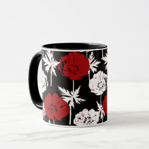 Röda, vita blommor på svart mugg