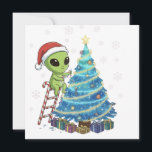Rolig Söt Alien Tomte Dekorerar Rymd Jul Julkort<br><div class="desc">Gör dig redo för en extraordinär julfirande! Denna charmiga och humoristiska design visar en vänlig grön utomjording i en tomtehatt som glatt dekorerar ett festligt julträd. Titta noga och du kommer att se de unika, kosmiska dekorationerna, inklusive planeter, stjärnor, en rymdfarkost och en UFO! Stående på en sockerrörsstege är denna...</div>