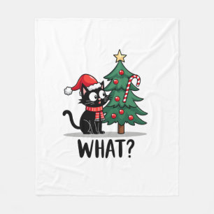 Rolig svart katt present som knuffar julgran över fleecefilt