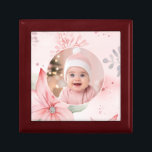Rosa Blommigt Baby Första julklapp Minnesask<br><div class="desc">En delikat juldesign omger den utbytbara blommigten av ett baby för deras "första jul". Rosa poinsettia och gröna accents vilar på en underbar  rosa bakgrund. Allt det här ser vackert ut på den här keepépresentlådan.</div>