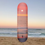 Rulla igenom gyllene Orange Sunset Skateboard<br><div class="desc">Skateboard ger en bild av en person som går genom solnedgångens gyllene rosa och orange. De färgstarka strålarna skapar en orb som silhuetterar valkaren.</div>