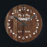 Rustic Barn Wood Plank Bröllop Rund Klocka<br><div class="desc">Bröllop-väggklocka med en rustik träbakgrund. Anpassa den rustiska lingklockan med ett par efternamn och bröllop datum. Gör en unik gåva till nygifta eller till husuppvärmning.</div>