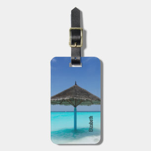 Scenisk tropisk strand med tunn paraply bagagebricka
