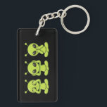 Se, Hör, Tala Inte Ondt<br><div class="desc">Lägg till en lekfull kosmisk twist på ett tidlöst budskap med denna söta nyckelring med tre utomjordingar. Med tre gröna utomjordingar som gör de klassiska ”se inget ont, höra inget ont, tala inget ont”-poserna, blandar denna design humor med en antydan om mystik från bortom stjärnorna. Perfekt för science fiction-fans, utomjording-entusiaster...</div>