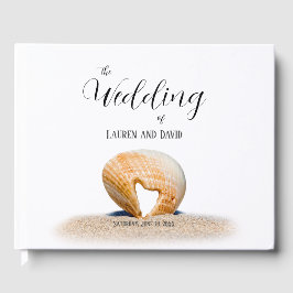 Seashell med ett hjärta på sand vid Beach. Gästböcker