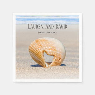 Seashell med ett hjärta på sand vid Beach. Pappersservett