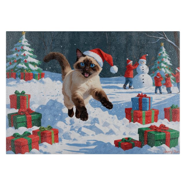 Siamesisk katt springer i snö med julhatt (Framsidan)