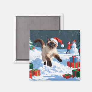 Siamesisk katt springer i snö med julhatt magnet