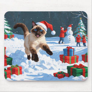 Siamesisk katt springer i snö med julhatt musmatta