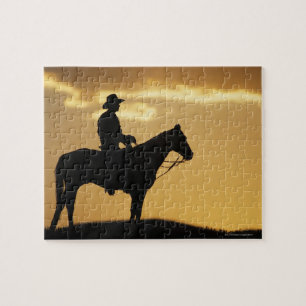 Silhouette av cowboyen på hästrygg på solnedgå pussel
