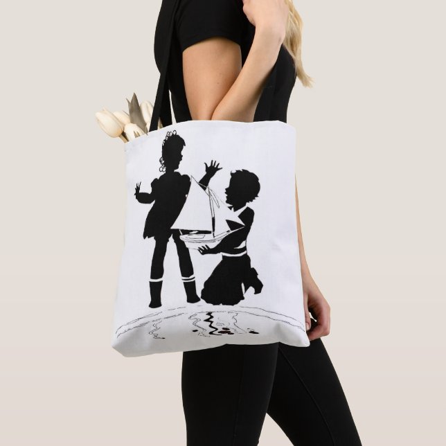 Silhouette med flicka och pojke och modellbåt tygkasse (Närbild)