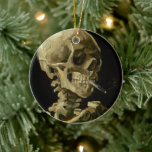 Skeleton med brinnande cigarett | Vincent van Gogh Julgransprydnad Keramik<br><div class="desc">Skullet på en Skeleton med brinnande cigarett (1886) av Vincent van Gogh är en slående och okonventionell likörmålning som innehåller ett mänskligt skalle med en tänd cigarett mellan tänderna. Bakgrunden till mörken förstärker det skelettala figur, medan rökens lilla rök ger en känsla av genombrott och ironi. Denna teckning, som skapades...</div>