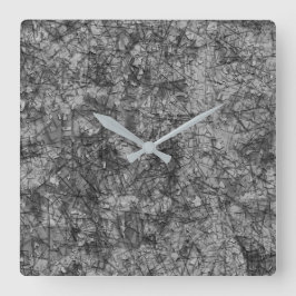 Skinnad på ett lätt fläckat grått och svart fyrkantig klocka