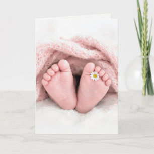 Små flickfötter med en vit tusenskönast kort