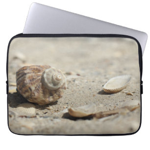 Snäckskal på sanden vid havet laptop sleeve