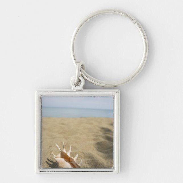 Snäckskal på sandig strand fyrkantig silverfärgad nyckelring (Framsidan)
