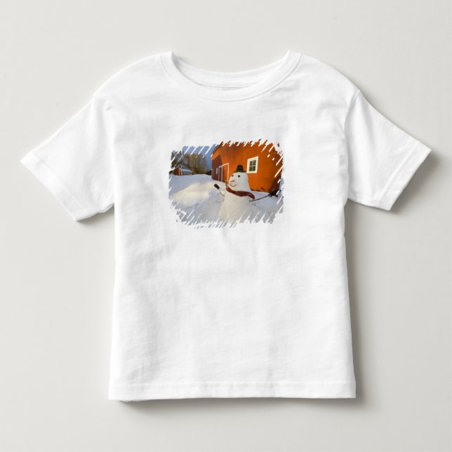Snöman framför röd lada i Columbia Falls Tee Shirt (Framsida)