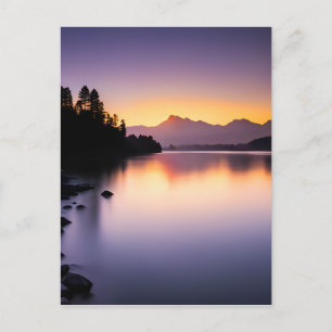 Solnedgång reflekterande över en sjö vykort
