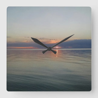 Solnedgången över vatten tar tid på fyrkantig klocka