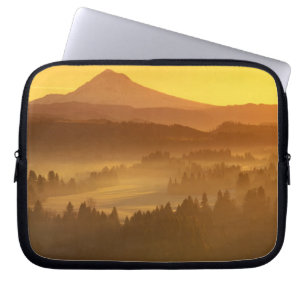Soluppgångens orange färgtonar dimman i dalen i laptop sleeve