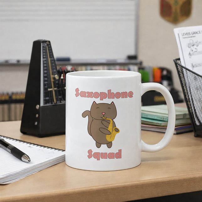 Söt katt som spelar saxofon “Saxofon-squad” Musik Kaffemugg (A mug with a cute cat playing the saxophone and the words saxophone squad in pink.)