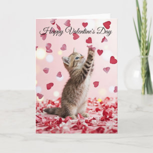 Sött litet kattunge fångar hjärtformade blomblad p kort